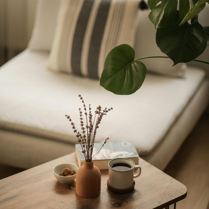 Detalle de mesa de café con taza, florero y planta monstera
