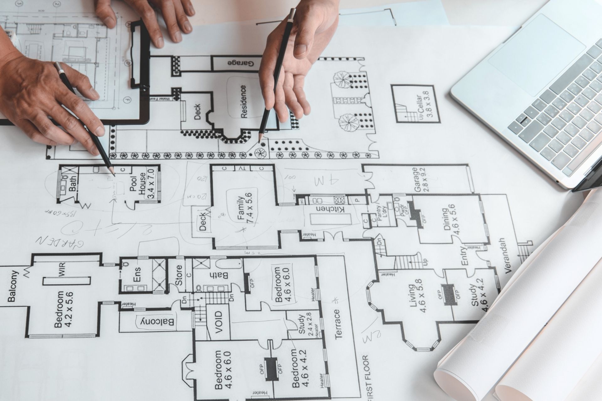 Manos trabajando sobre planos arquitectónicos de distribución de espacios