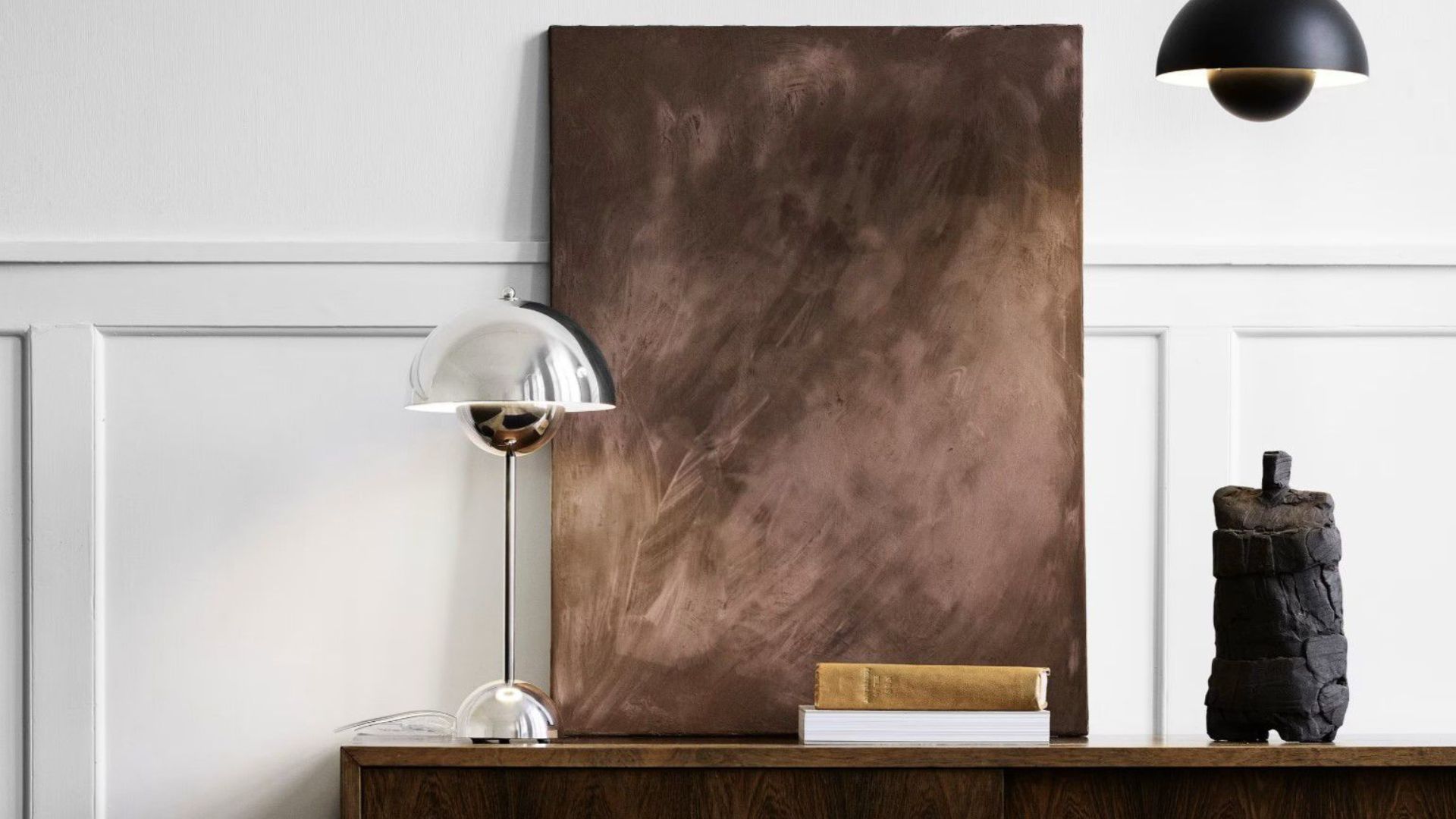 Espacio minimalista con cuadro artístico marrón, lámpara de pie y objetos decorativos